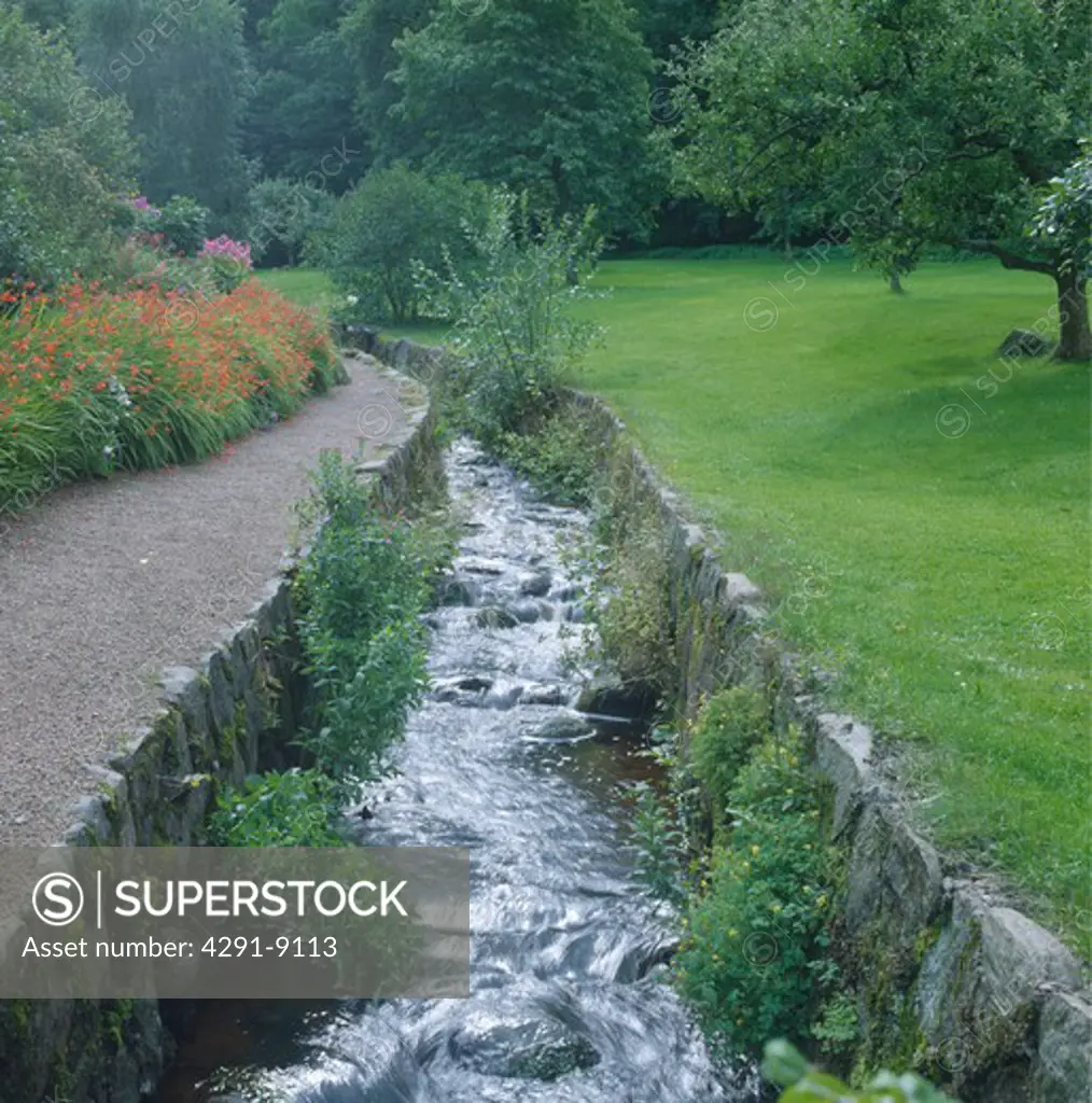Sunken stream between stone banks in country garden