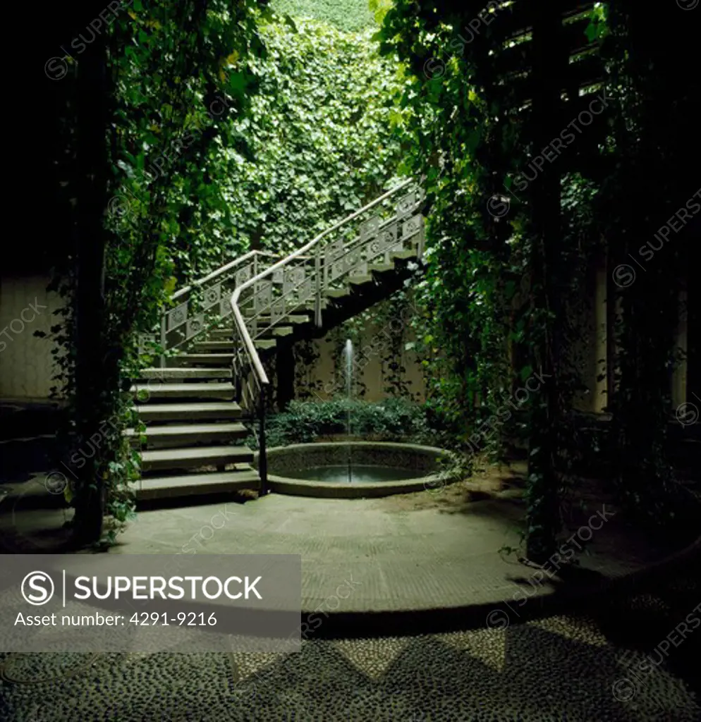 Steps leading down to circular pool in sunken paved garden