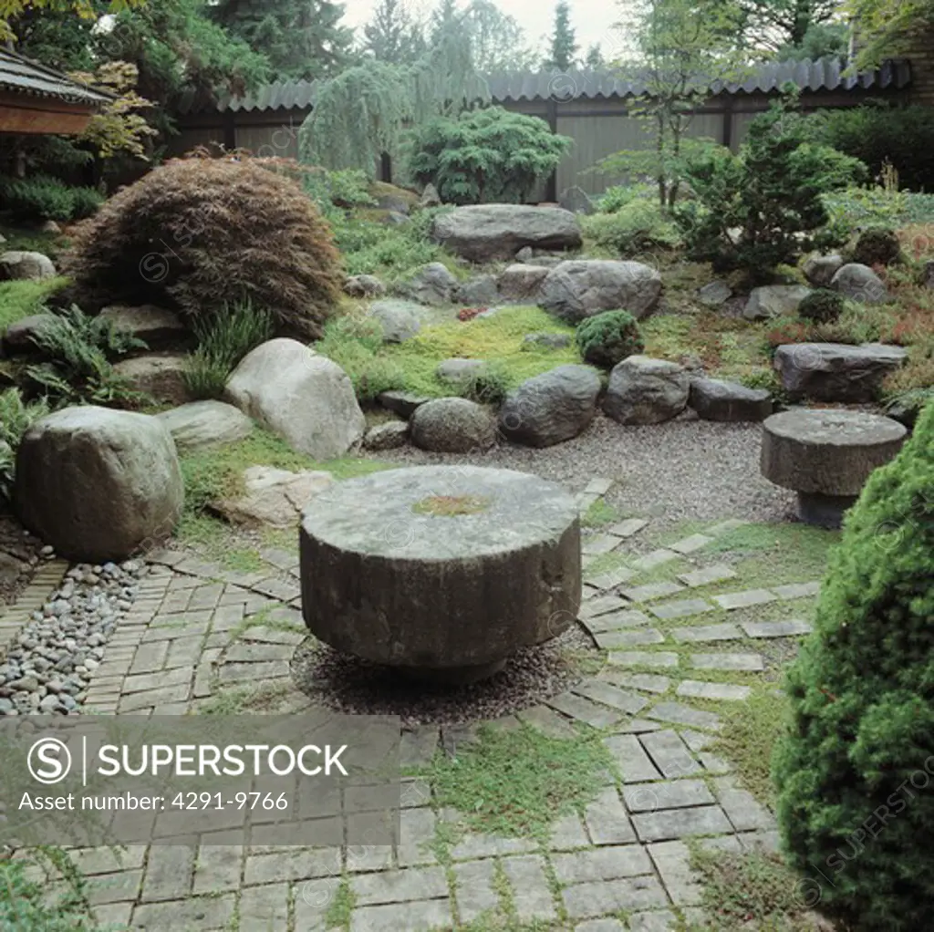 Circular stone table in paving in oriental-style country garden