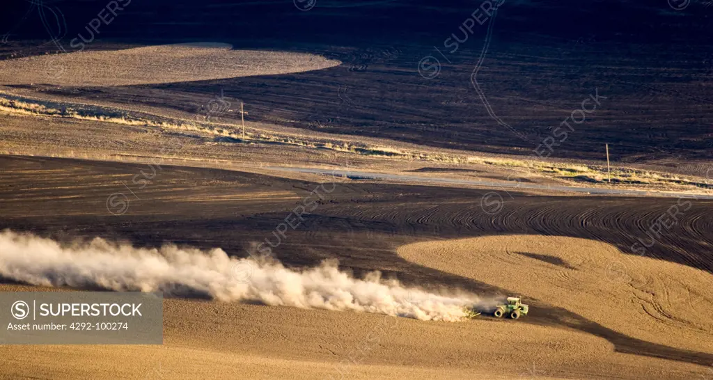USA, Eastern Washington, tractor plowing field and turning up dust for winter field