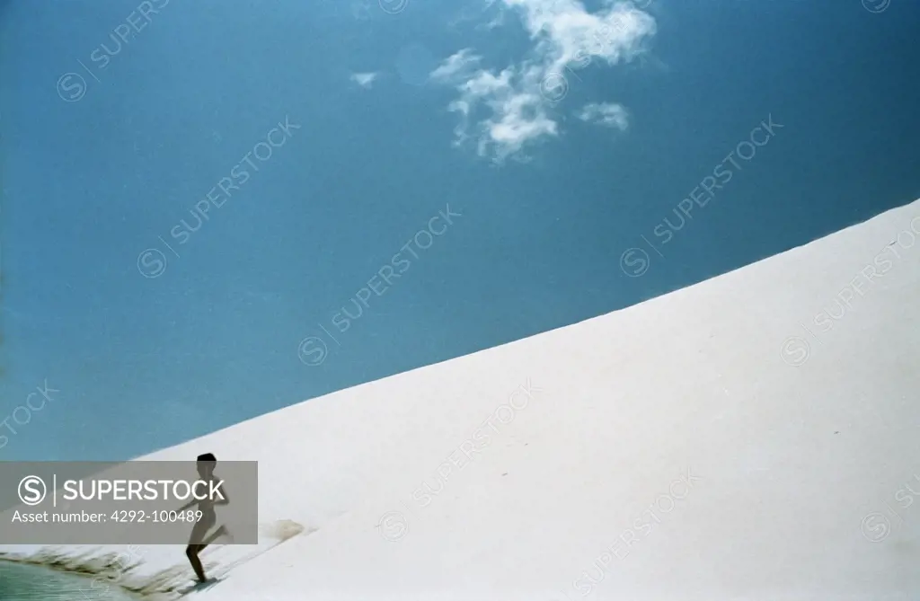 boy running on dune of Lencois Maranhense desert , Maranhao, Brazil