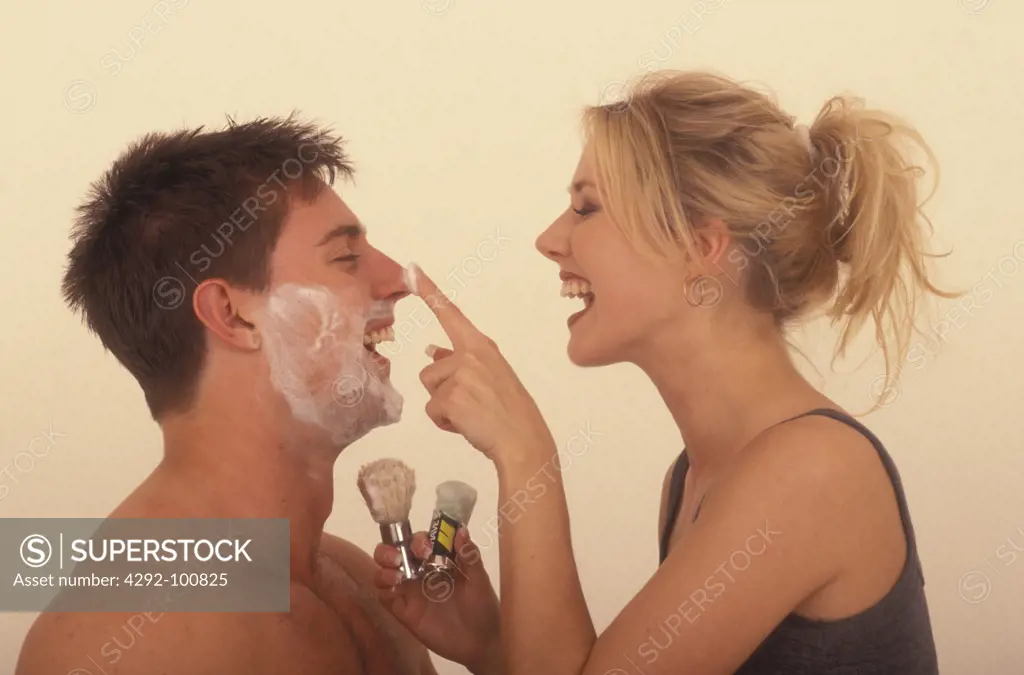 Playful woman shaving man's face
