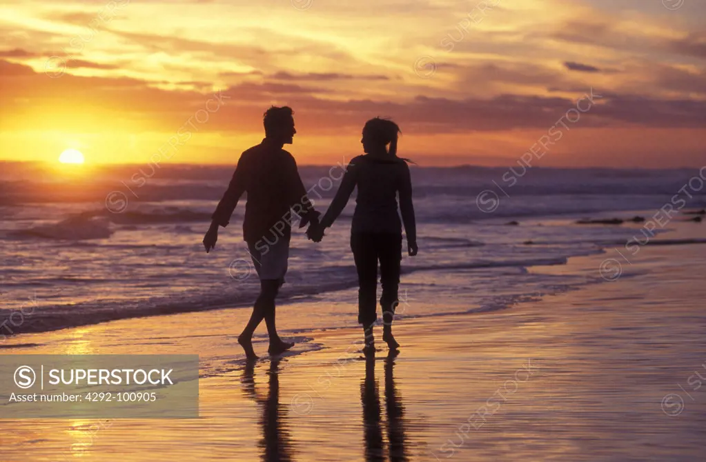 Couple walking on beach and sunset