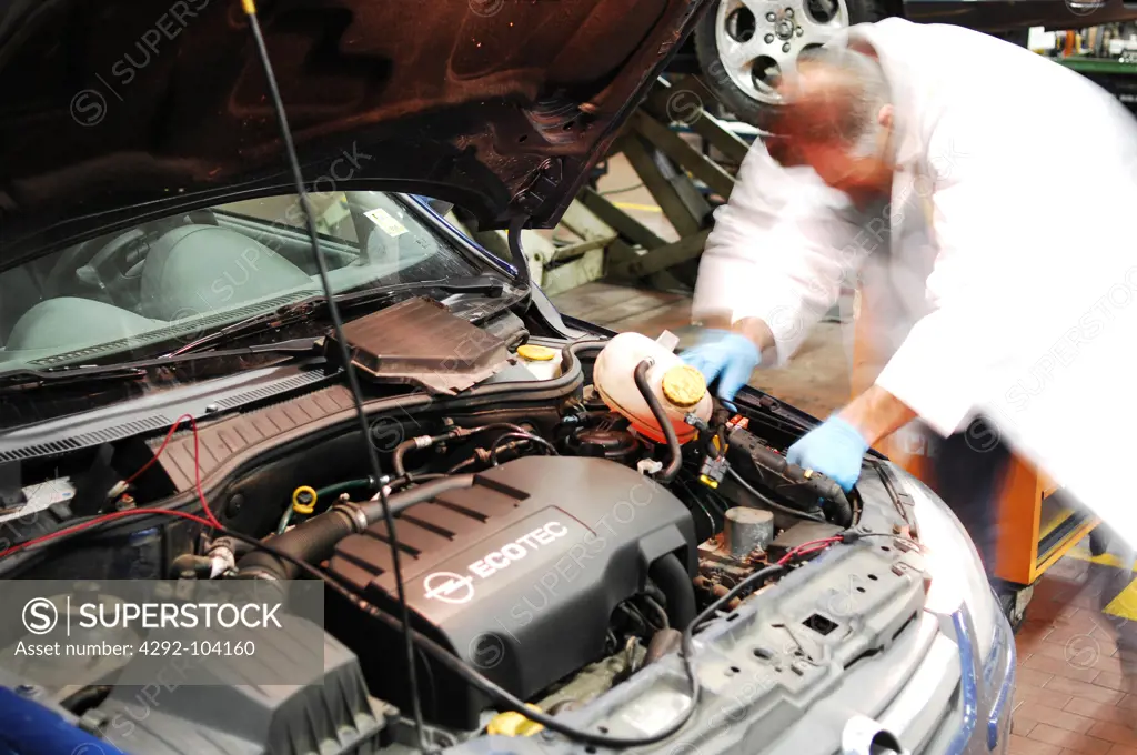 Mechanic in repair garage checking car's engine
