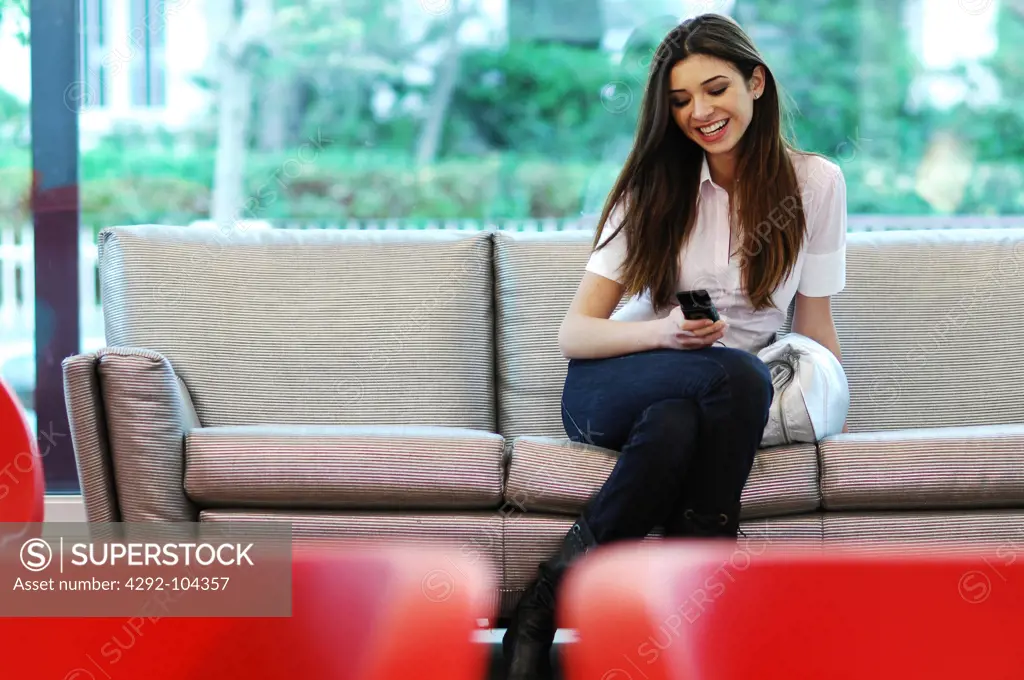 Woman sitting on sofa with mobile