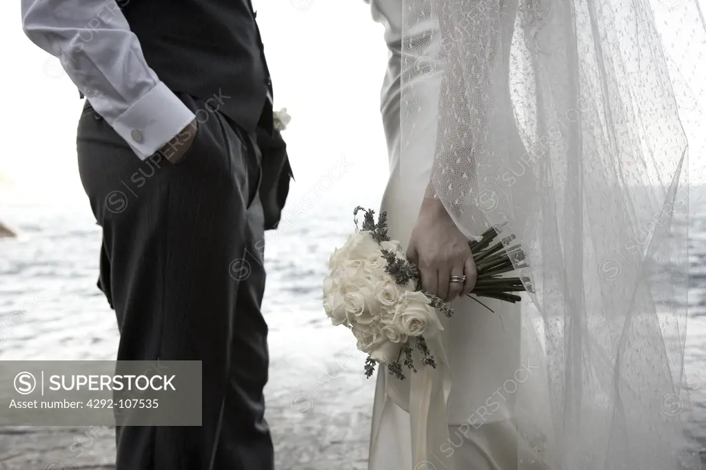 Bride and groom standing by sea