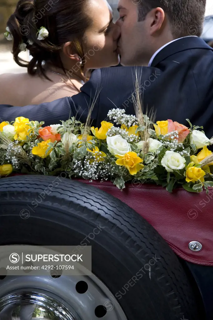 Bride and groom kissing in a convertible car
