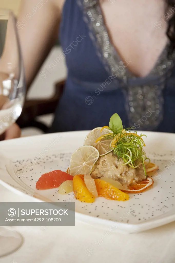 Woman lunching, in foreground citrus salad