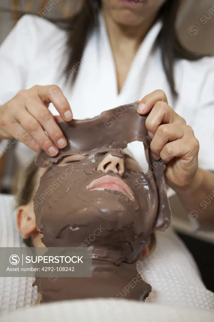 Beautician applying facial mask of chestnut musk