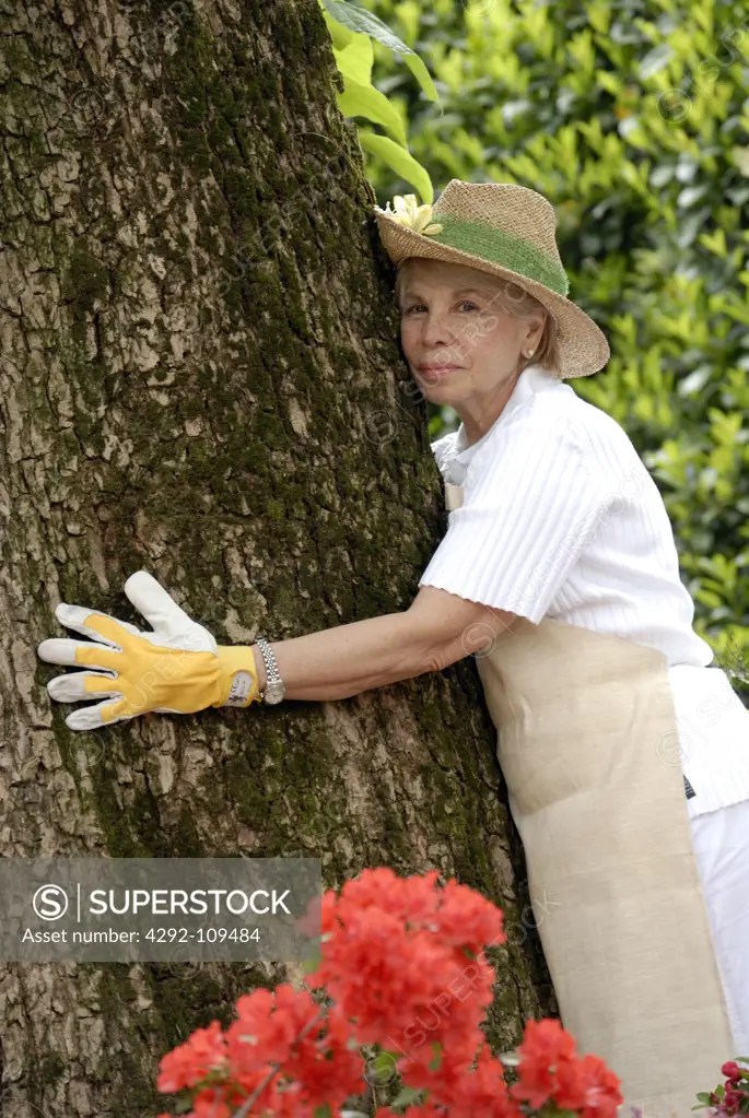 Senior woman hugging tree trunk