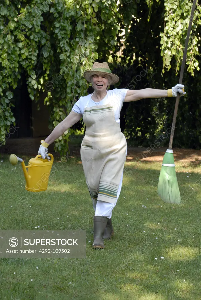 Senior woman with watering can and broom