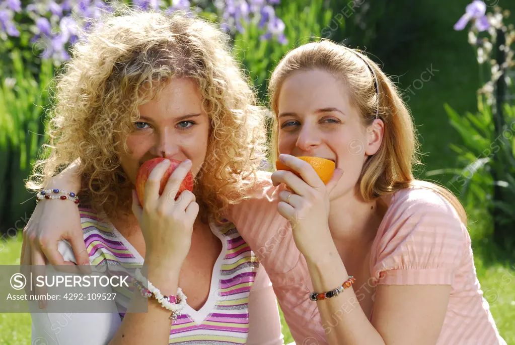 Two friends eating fruits