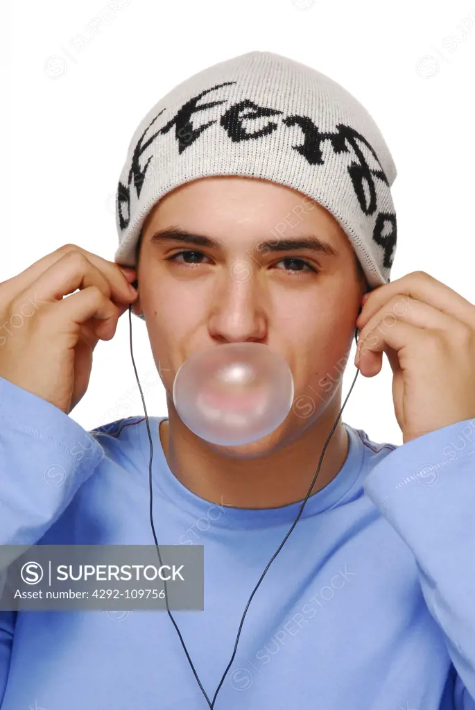 Teenage boy blowing blowing g gum bubble and listening to music