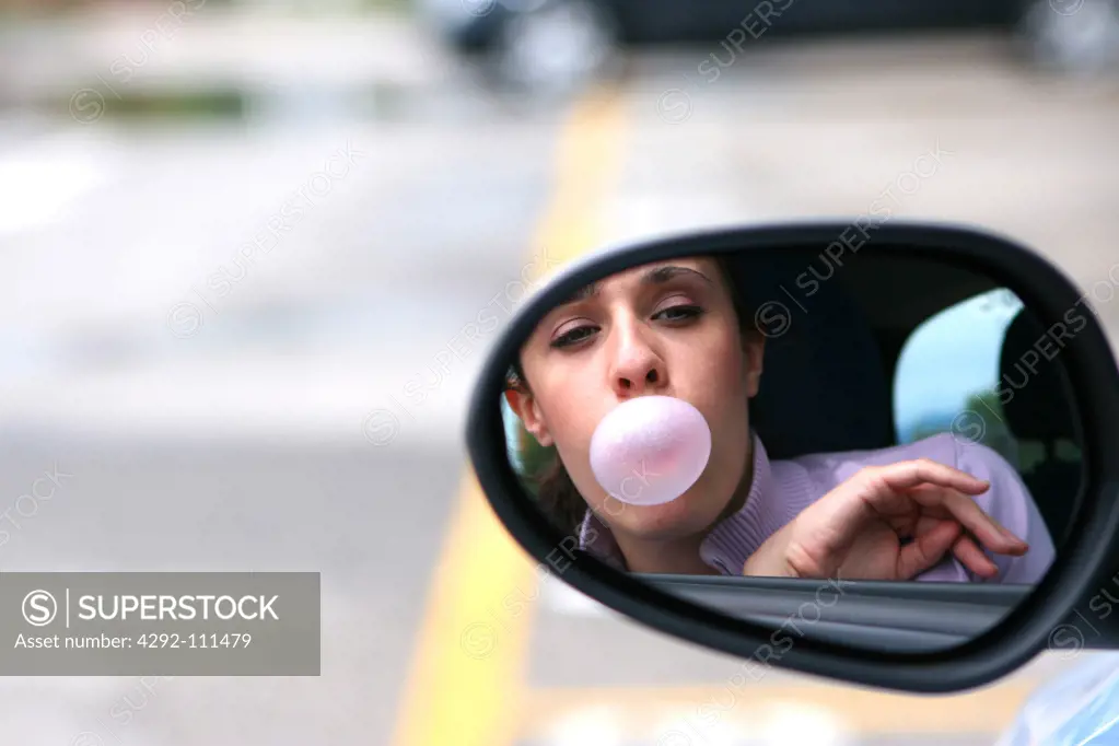 Woman in car blowing bubble gum