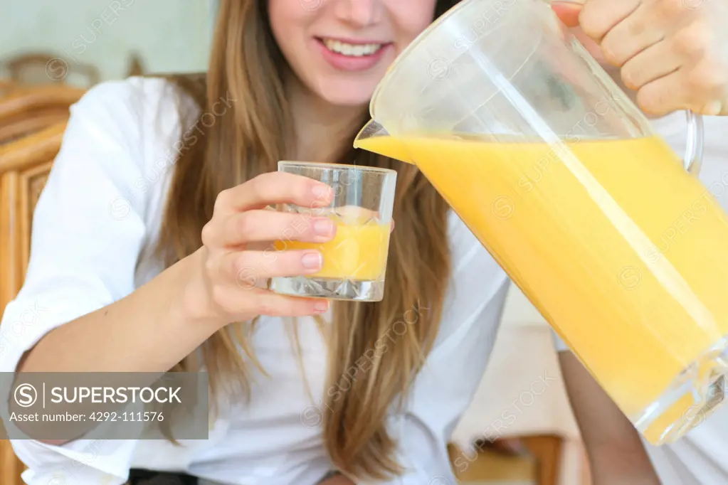 Couple having breakfast, man serving orange juice to woman