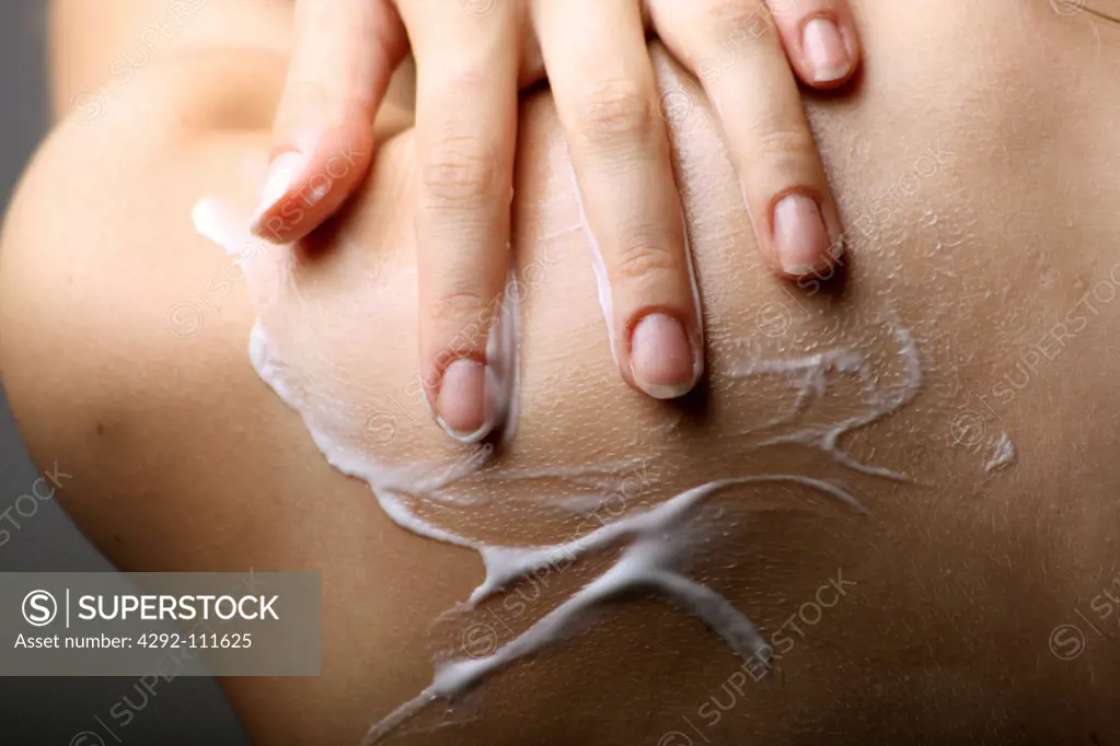 Woman applying moisturizer on back