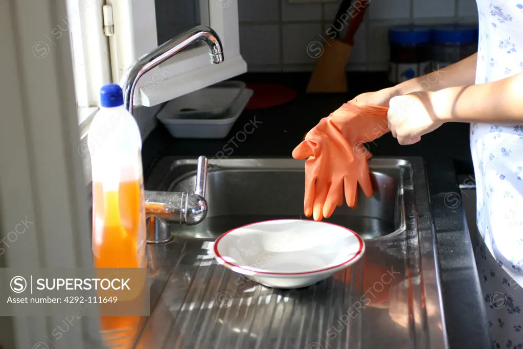 Woman in the kitchen wearing gloves to wash dishes