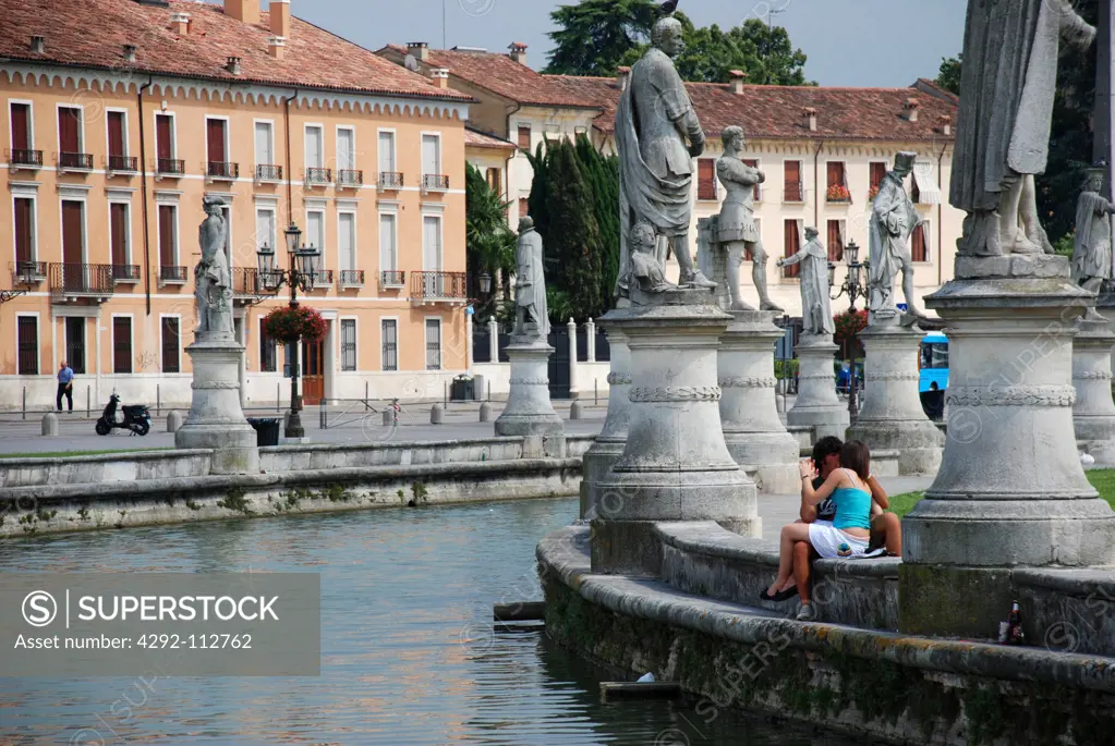 Two teenagers kissing by the water in Piazza del Prato della Valle in Padova, Italy