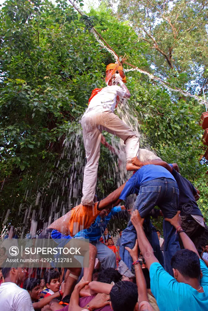 India, Goa, Panjim, Man on a human pyramid grabbing prize.