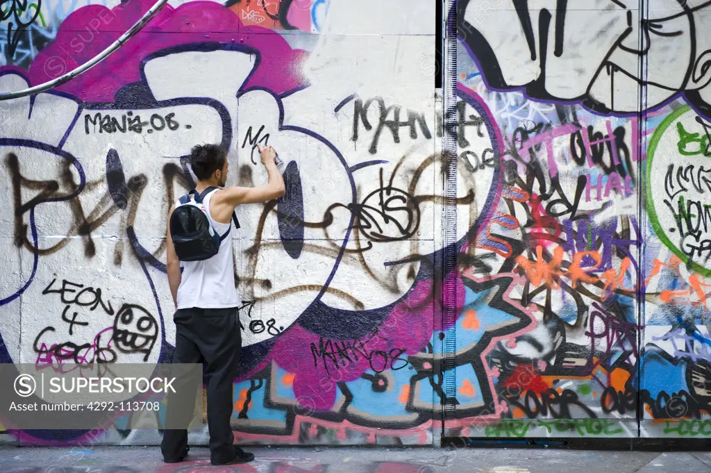 England, London, Graffiti artist spray painting a wall