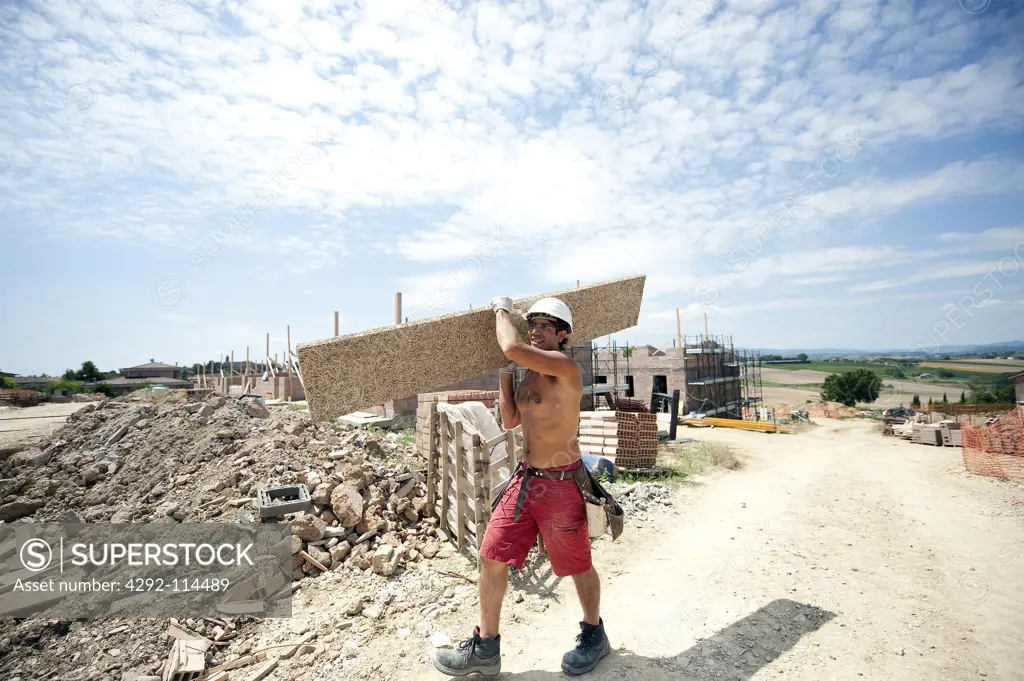 Worker with plank at construction site