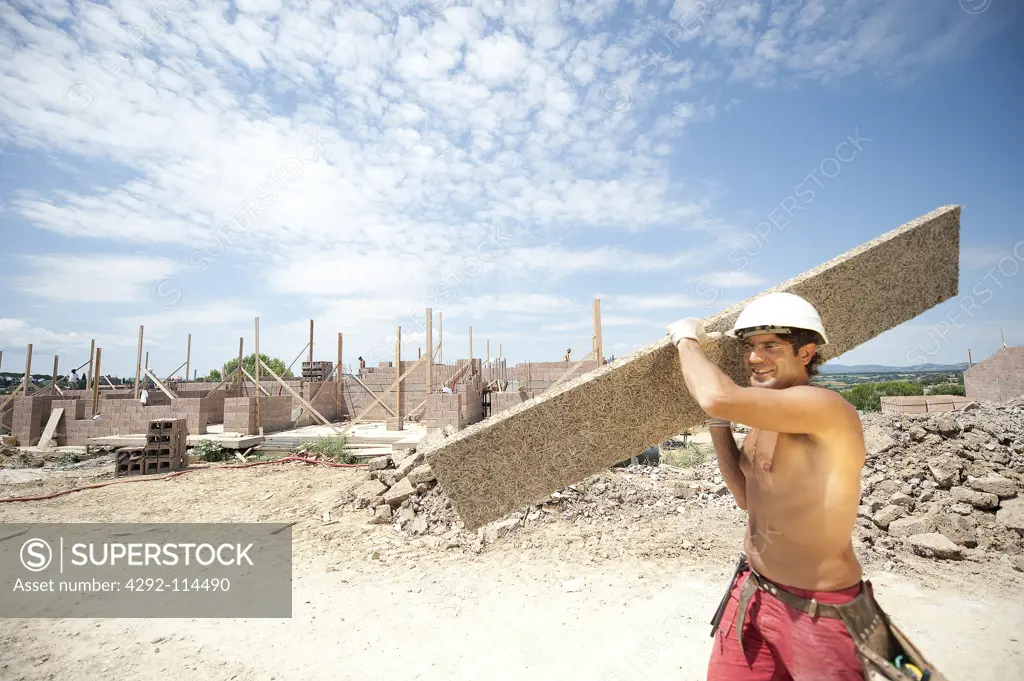 Worker with plank at construction site