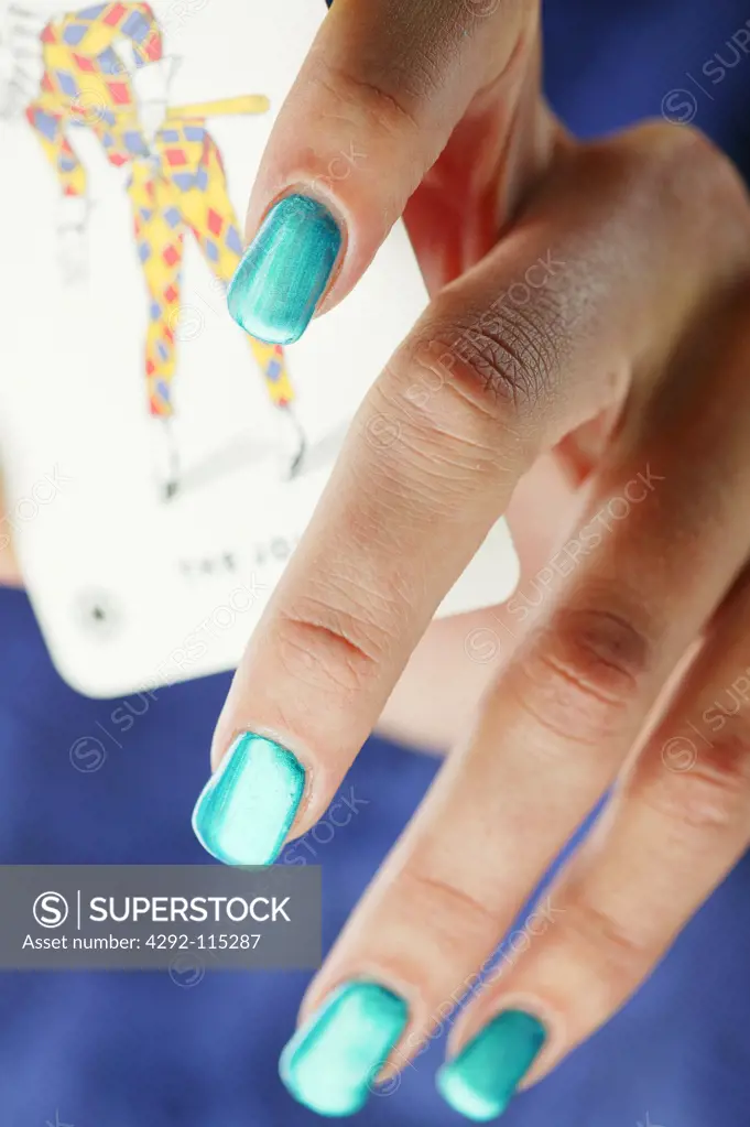 Close up of woman's hand hiding a joker playing card