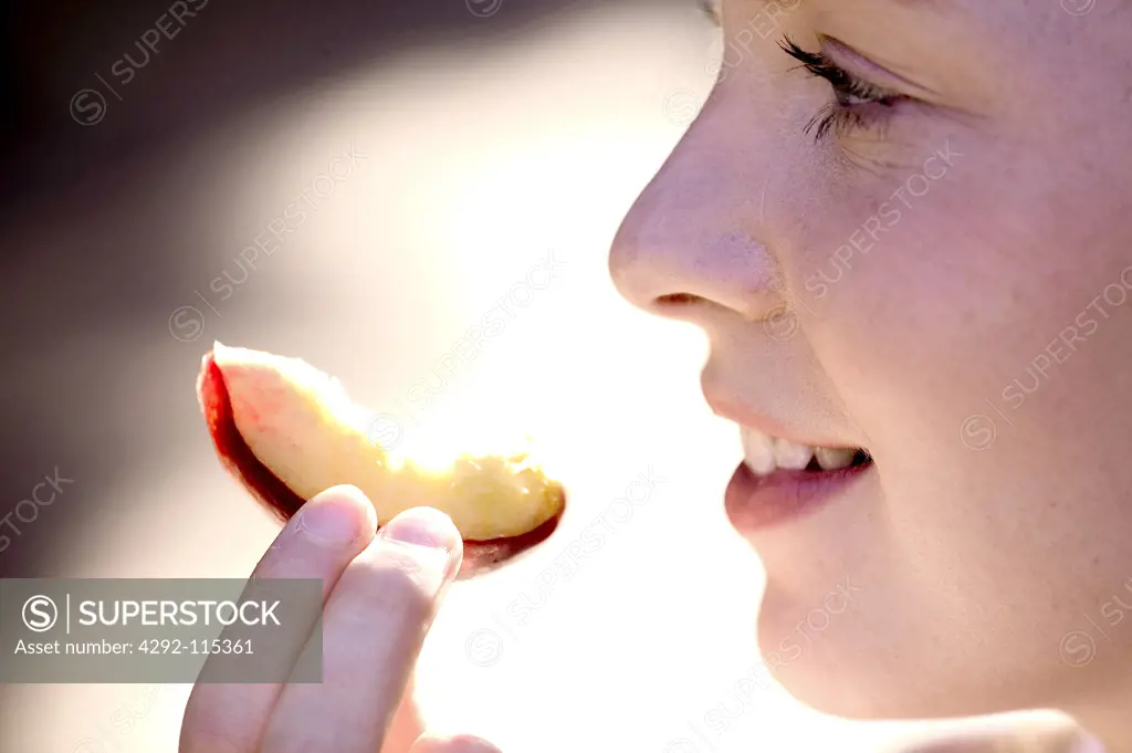 Woman eating a slice of peach