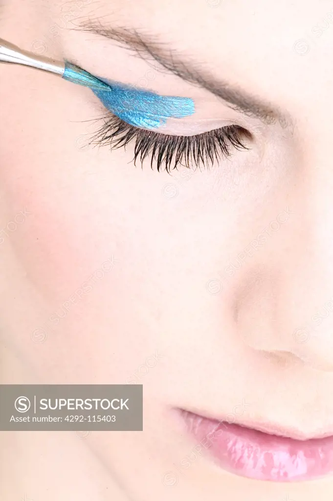 Woman applying eyeshadow, face close up