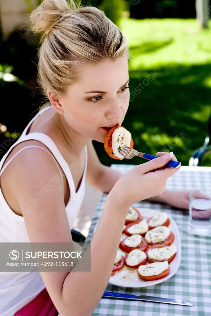 Woman eating tomato and mozzarella