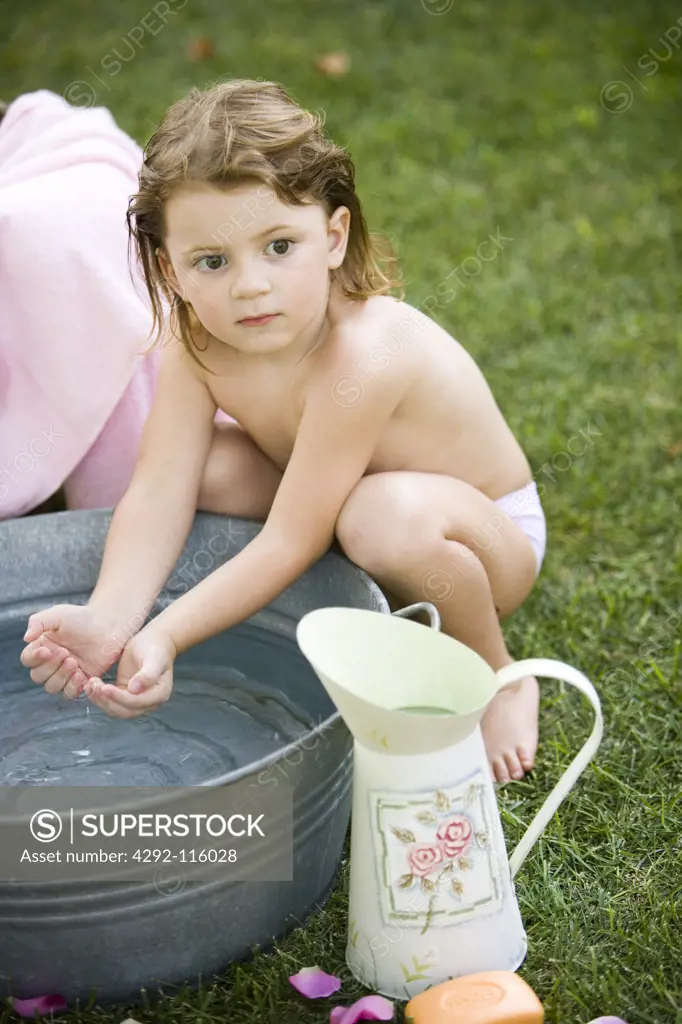 Little girl playing with water in a basin