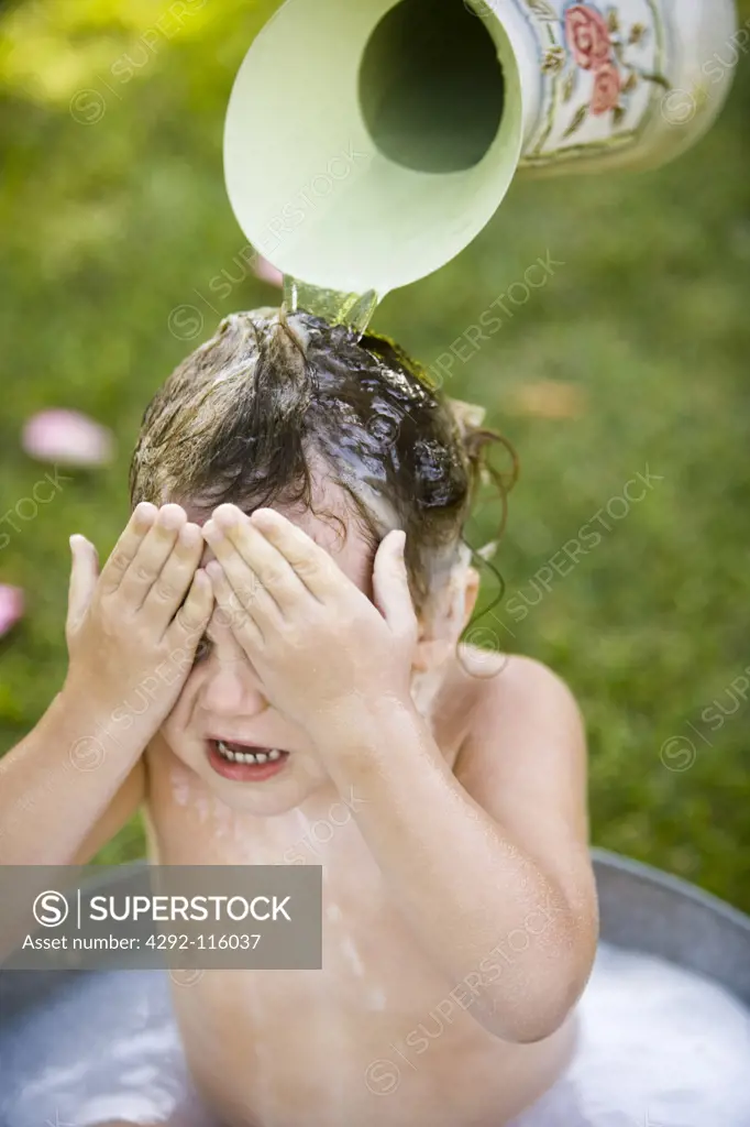 Little girl having a bath outside in a basin