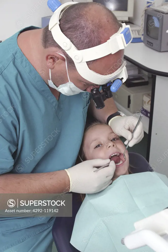 Dentist examining young female patient