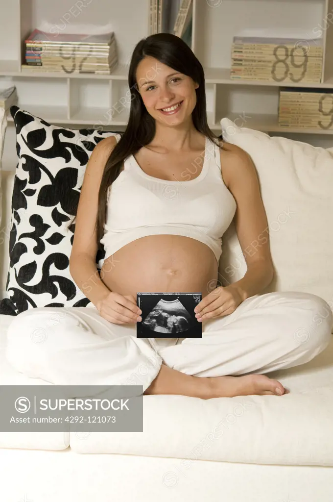 Pregnant woman showing ultrasound photograph of her baby