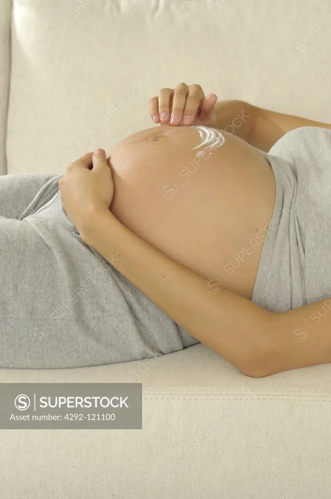 Pregnant woman applying moisturiser on her belly