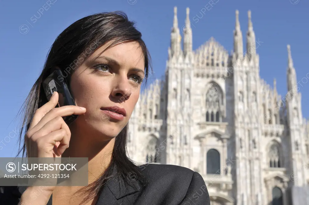 Italy, Lombardy, Milan. Businesswoman using mobile and view of the Duomo in background