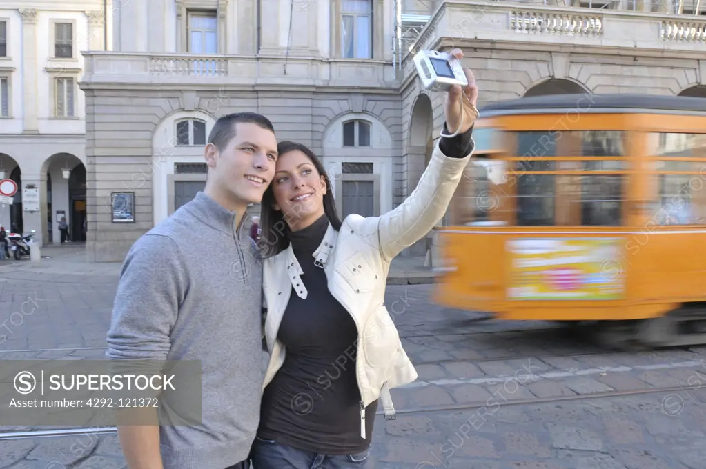 Italy, Lombardy, Milan, Piazza della Scala, couple taking picture of themselves with digital camera