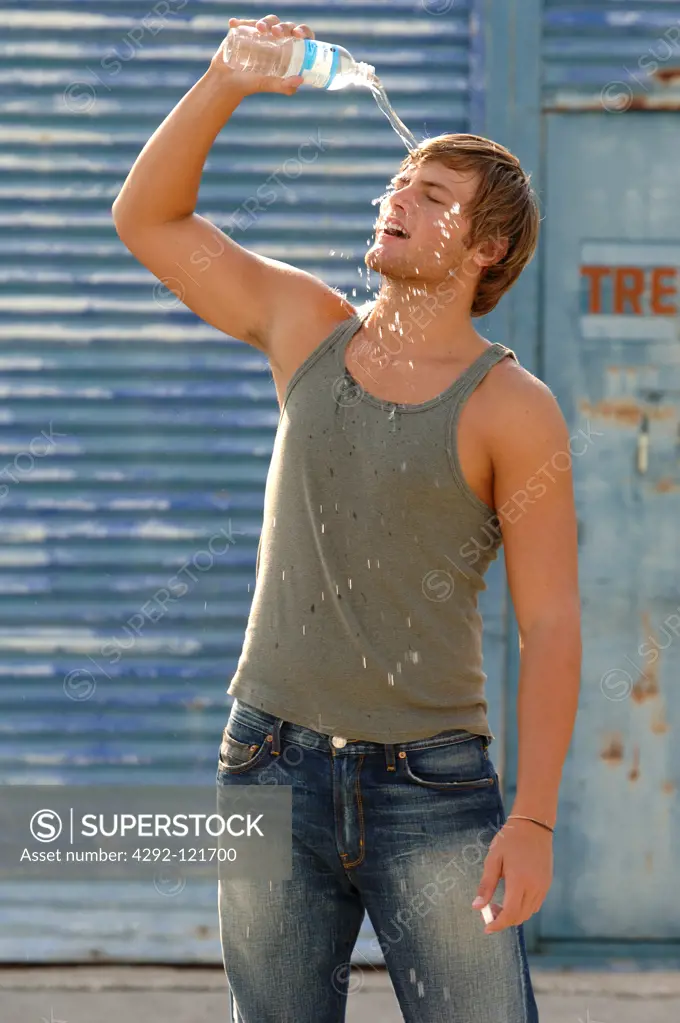 Man pouring water from a bottle on his face