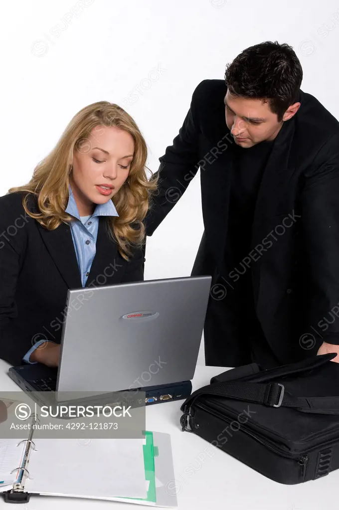 Businessman and businesswoman in office working on laptop