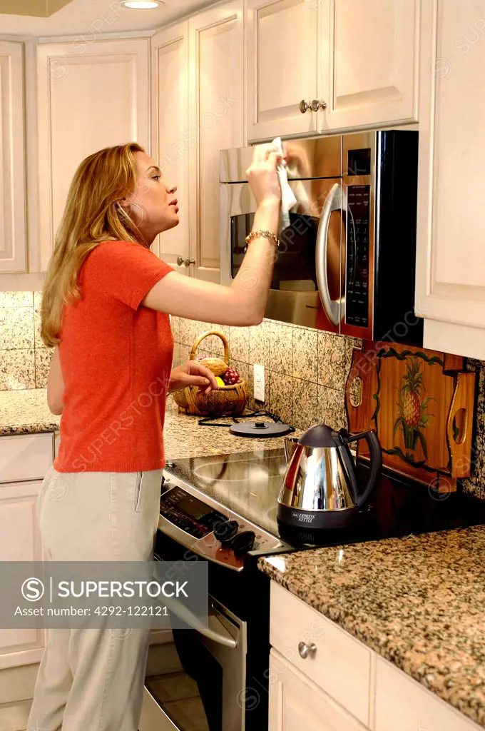 Woman in the kitchen cleaning mricrowave oven