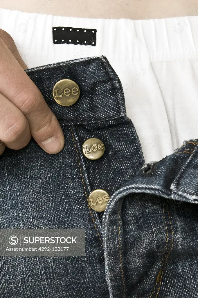 Close-up of a man's hands buttoning his jeans