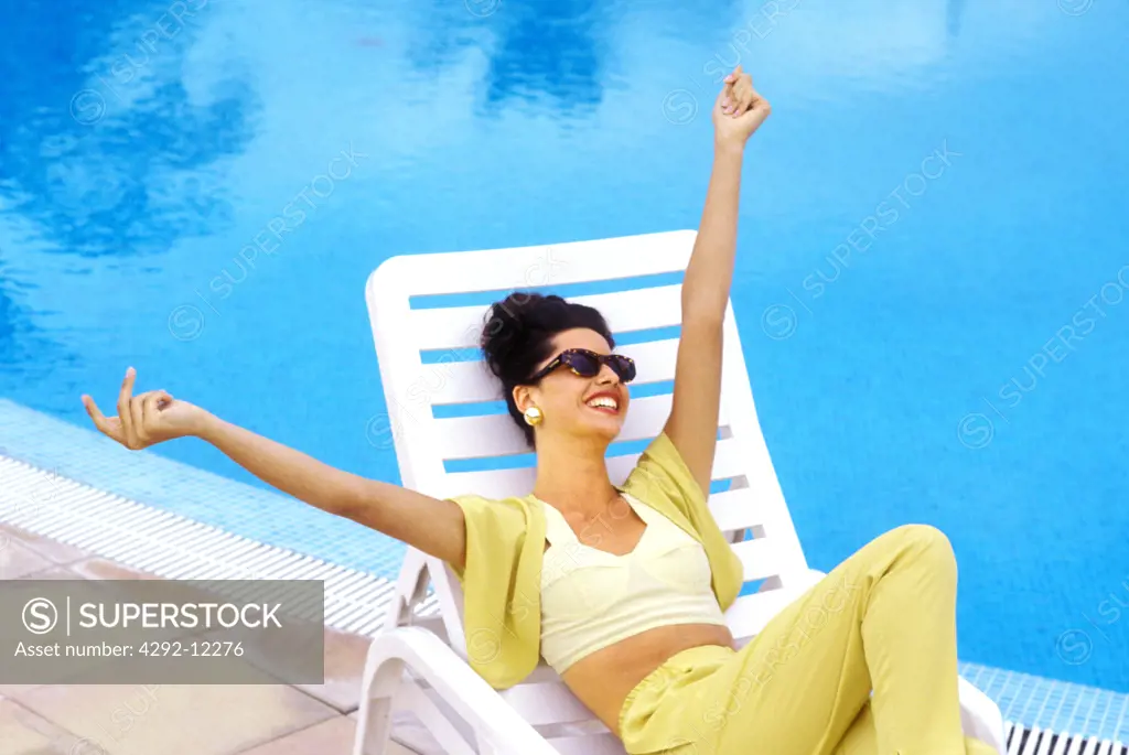 Young woman lying on a deckchair at the swimming pool