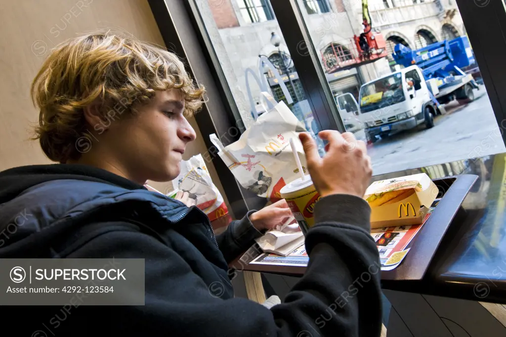 Teenage boy eating at fast food