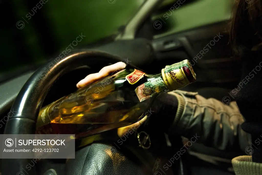 Man with whisky bottle sitting in car