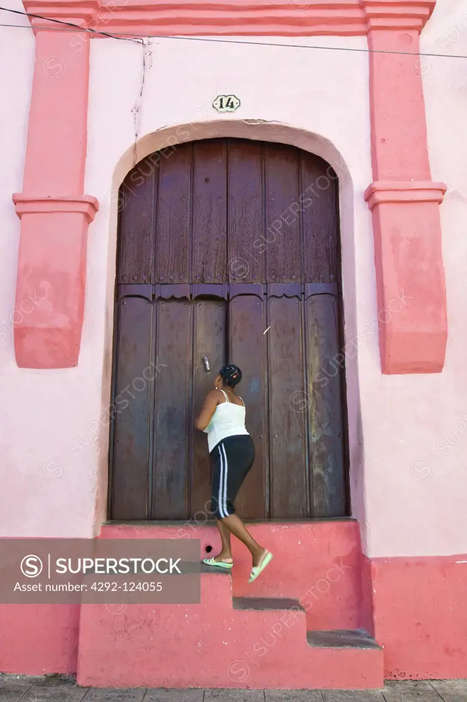 Cuba, Camaguey, local woman opening door building