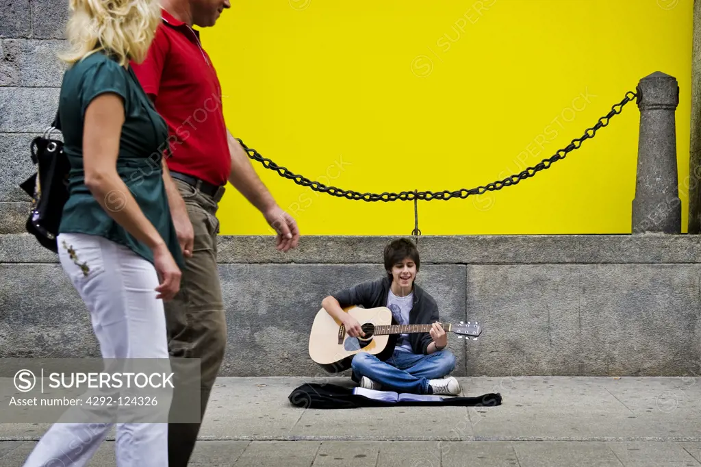 Teenage boy playing guitar in the street