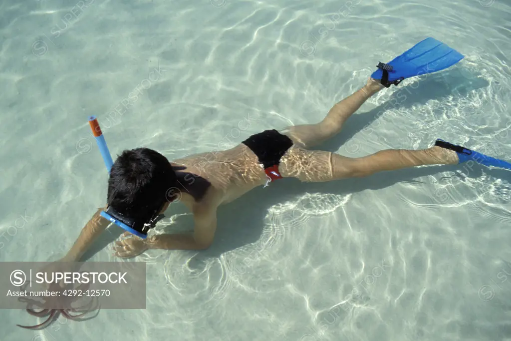 Little boy with snorkel playing with octopus in shallow water
