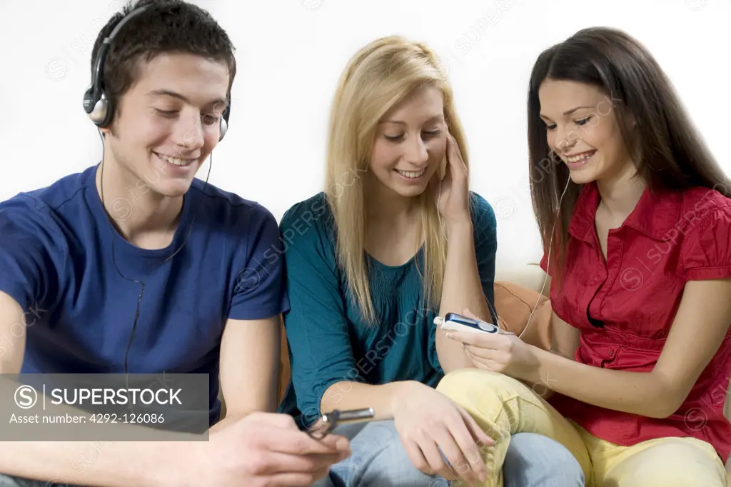 Three friends  listening to music with mp3 player