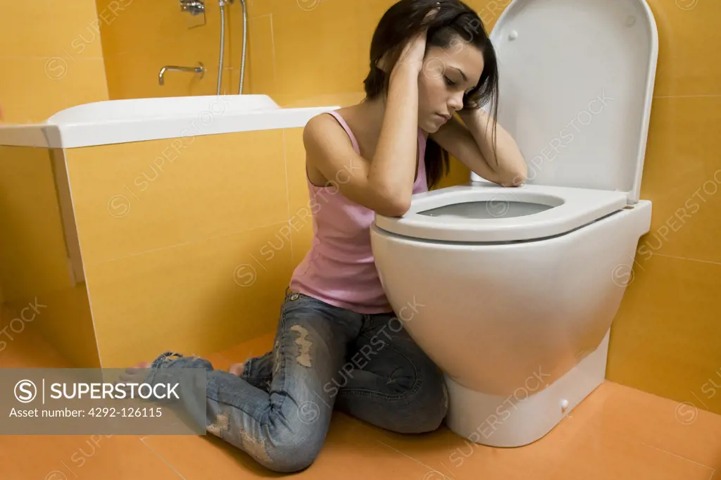 Teenage girl sitting next to toilet