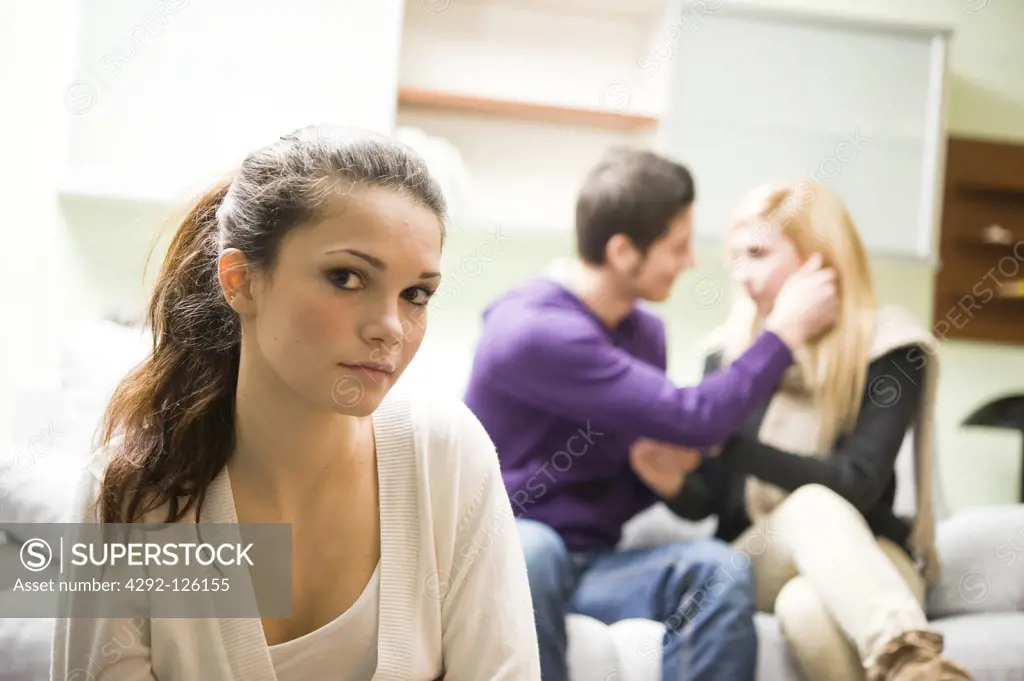 Unhappy girl and teenage couple in backround